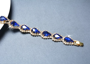 Détail du bracelet en cristal bleu en forme de goutte avec strass blancs sur monture dorée
