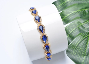 Détail d'un bracelet en cristal avec pierres bleues en goutte sur support blanc