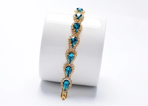 Détail du bracelet doré avec cristaux bleus en goutte et petits strass brillants