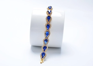 Détails d'un bracelet doré orné de cristaux bleus en goutte et de strass scintillants