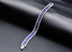 Detail view of silver bracelet with blue and clear crystals on black leather background