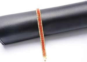 Detailed view of a gold-plated bracelet featuring red and white rhinestones on a black roll