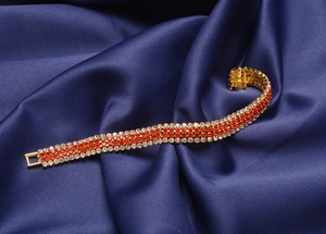 Detailed shot of three-row gold plated rhinestone bracelet on dark blue silk fabric