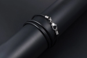 Close-up of black braided cord necklace with silver lobster clasp on a display stand
