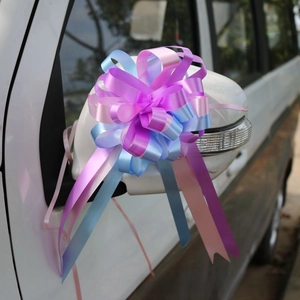 Detail of pink and blue gradient decorative ribbon bow tied on a car side mirror