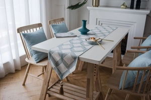Detail of grey-blue cotton linen table runner with geometric pattern and tassels