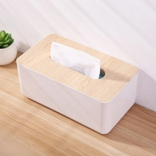 Detail view of a minimalist white tissue box with a natural wood grain lid finish.