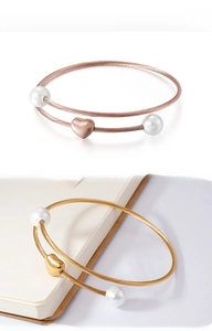 Detail of rose gold and gold heart-shaped charm bracelets with shell pearls