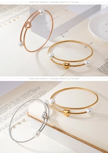 Detailed macro view of heart charm and pearl accents on double-layer cable bangles