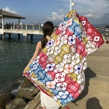 Ethnic geometric print cotton beach shawl worn by a model on a sunny seaside pier