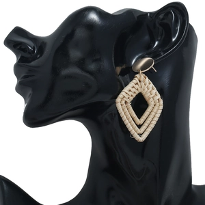 Boucles d'oreilles bohèmes en rotin avec clou doré présentées sur une tête de mannequin