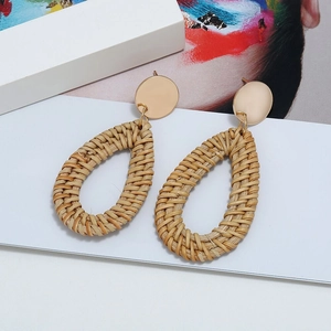 Gros plan détaillé de boucles d'oreilles bohèmes en rotin avec clous dorés ronds