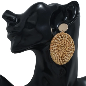 Détail macro de boucles d'oreilles rondes en rotin tressé avec clous dorés sur mannequin