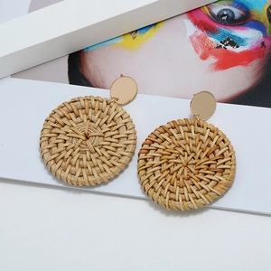 Gros plan de boucles d'oreilles bohèmes rondes en rotin avec clous dorés sur magazine