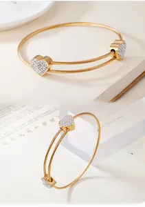 Detail view of gold cable bracelet featuring heart-shaped charms with sparkling zircon pavé