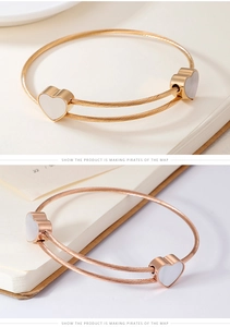 Detail of rose gold wire rope bracelet featuring heart charms with white shell inlay