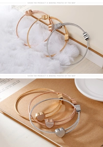 Detailed view of three-tone steel cable bracelets with heart shell inlays in gold and silver