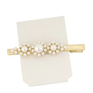 Elegant gold hair clip with white pearl flower design on a white display card
