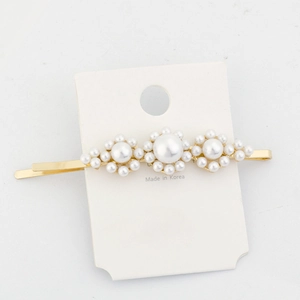 Detailed view of pearl hair clip with three flower shapes on a white display card