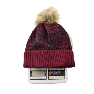 Detailed view of the 128.4g leopard print knit hat with a faux fur pom pom and ribbed cuff