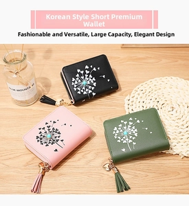 Tre portafogli con zip nei colori nero, rosa e verde con nappe a cuore su un tavolo di legno