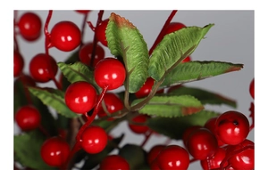 Close-up of vibrant red artificial berries and green leaves for Christmas floral DIY decor
