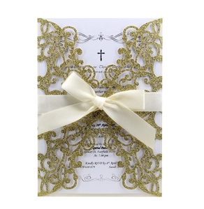 Macro shot of gold glitter laser cut wedding invitation with ivory ribbon and floral pattern