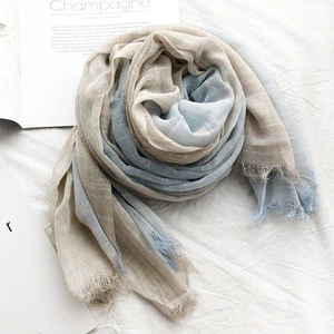 Detail of pleated two-tone scarf in light blue and beige with raw fringe edges