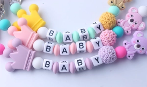 Detailed close-up of colorful silicone baby pacifier clips featuring koala and crown beads