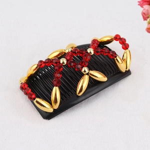 Close-up of magic hair comb with red faceted beads and gold oval accents on black base