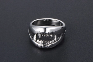 Detailed view of polished stainless steel crocodile teeth ring on dark background