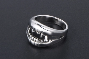 Detailed top view of a silver stainless steel crocodile teeth punk ring on textured background