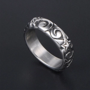 Vintage stainless steel ring with engraved stars and swirls on a textured dark background