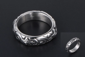 Macro shot of silver metal ring with engraved stars and swirls on a black background