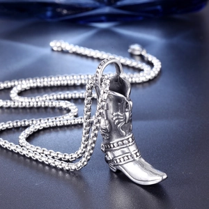 Macro detail of vintage silver stainless steel cowboy boot pendant with embossed rivet patterns
