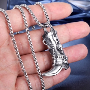 Close-up of a men's stainless steel skull boot pendant on a silver box chain necklace