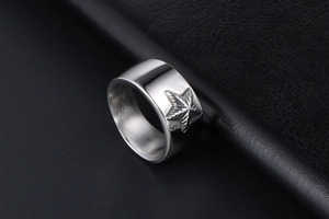 Vue détaillée d'une bague large en acier argenté avec étoile en relief sur fond de cuir noir