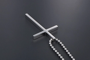 Close-up of polished silver steel inverted cross pendant on a beaded metal chain