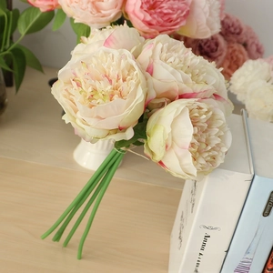 Close-up of artificial peony silk flowers with cream and pink petals in a home setting
