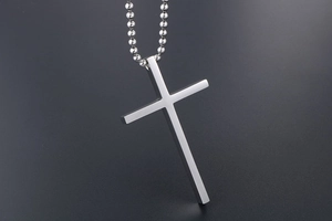 Detailed view of a polished stainless steel cross pendant necklace with a beaded chain