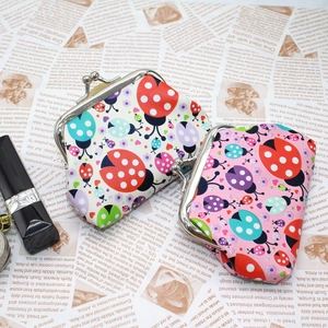 Detail of ladybug coin purses with vintage metal clasp and a lipstick for size scale
