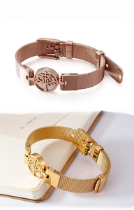 Detail of tree of life charm on mesh strap bracelet in rose gold and gold finishes
