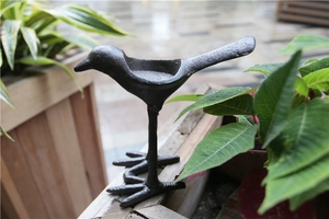 Gros plan d'un oiseau décoratif en fonte noire sur une clôture de jardin en bois