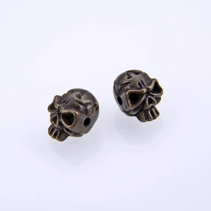 Macro shot of two bronze skull-shaped beads for DIY jewelry making with hole detail