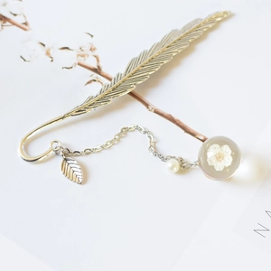 Detail of silver feather metal bookmark with dried white flower pendant and leaf charm
