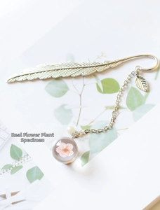 Detailed shot of silver metal feather bookmark with real pink flower resin pendant
