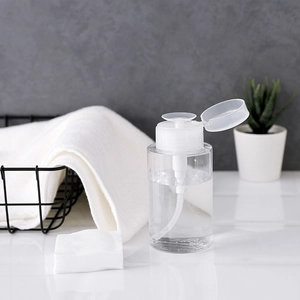 Clear plastic press pump bottle for makeup remover on a bathroom counter with towels
