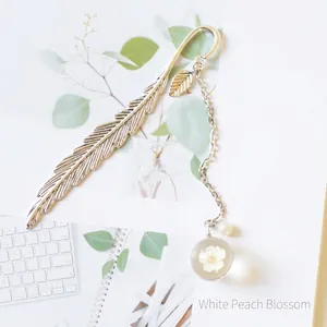 Detailed silver feather bookmark featuring a clear glass bead with dried white peach blossom
