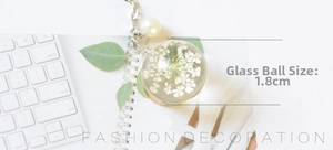 Detail of 1.8cm glass ball pendant with dried flowers and pearl charm on silver chain