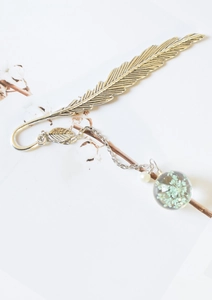 Silver metal feather bookmark with a transparent glass ball pendant containing dried flowers